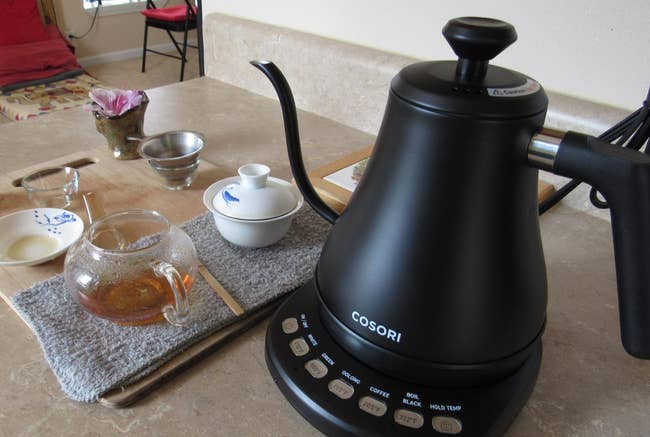 a reviewer shows the black kettle and tea made with it