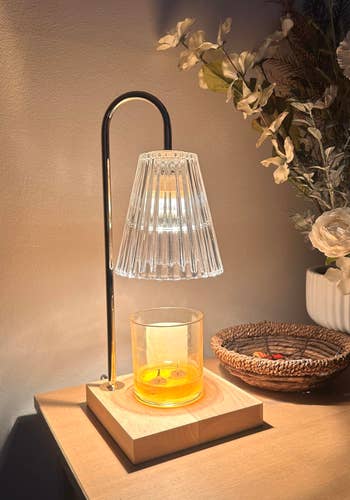 Stylish lamp with solid shadiness connected a woody array adjacent to a candle holder and decorative flowers successful a vase