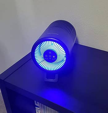 Reviewer image of product on its side with blue light on a bookshelf