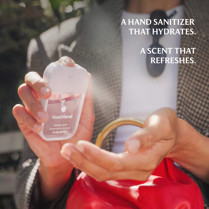 Person holding a Touchland manus  sanitizer with a spray mist and a reddish  container  visible, substance   reads 