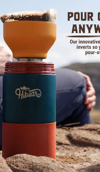A portable coffee-making bottle on sand with the text 