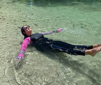 reviewer wearing black leggings while lounging in lake water