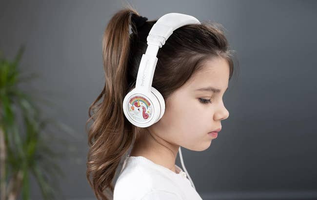 child model wearing white headphones with unicorn stickers