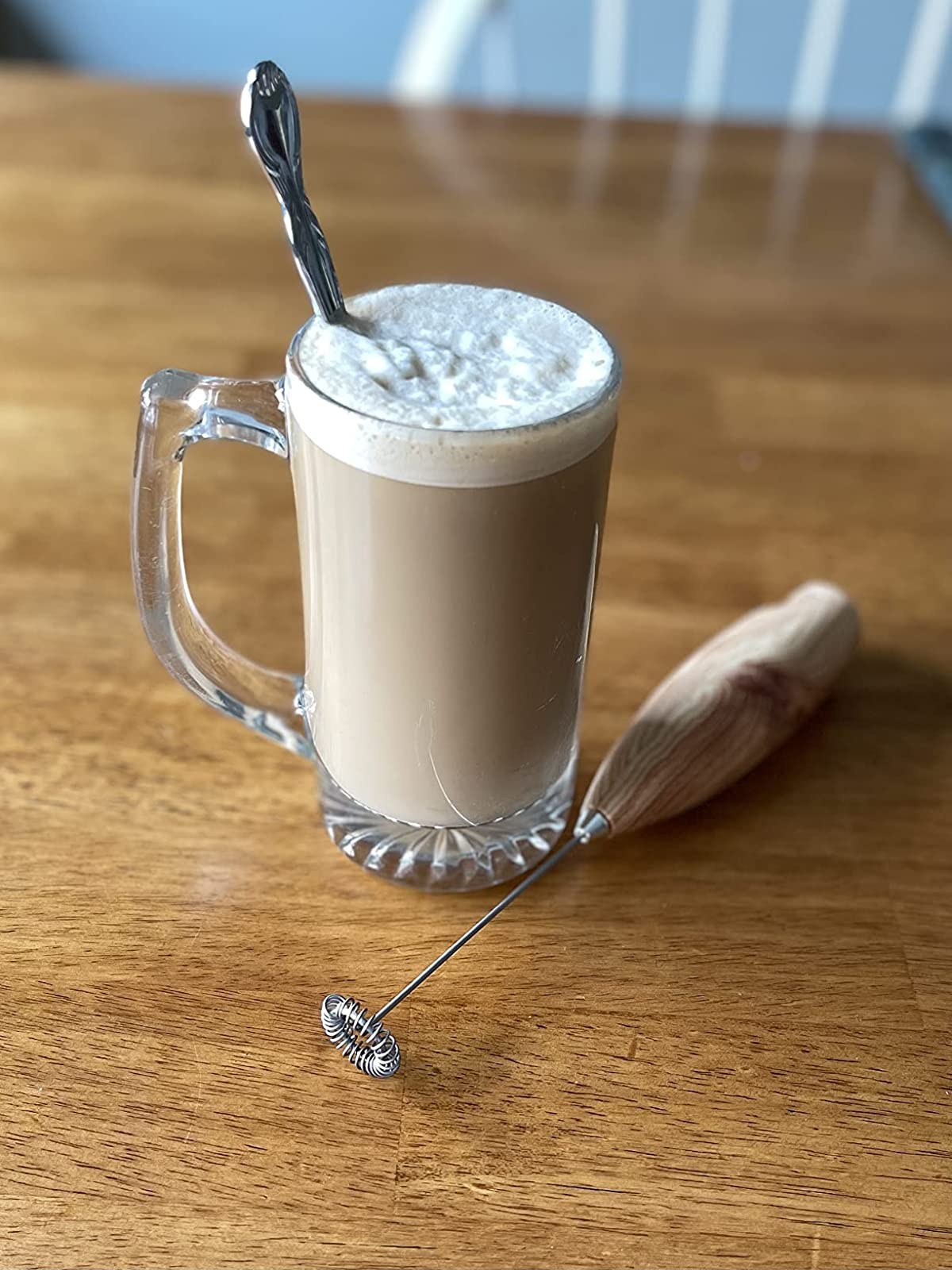 reviewer photo of a foamy drink next to the milk frother