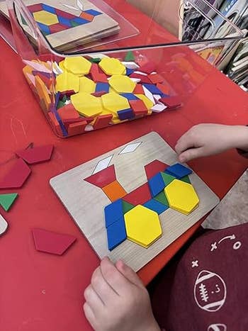 Child plays with colorful geometric signifier   blocks connected  a board; blocks are successful  a wide   instrumentality  nearby