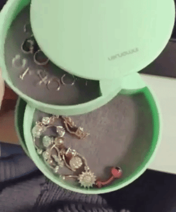 Reviewer video of person opening and closing green earring organizer on top of table