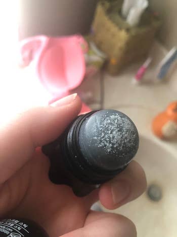 another reviewer holding scrub stick with black heads and white heads on it