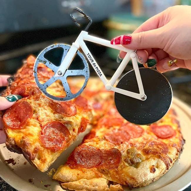 image of reviewer slicing pizza with the bicycle-shaped pizza cutter