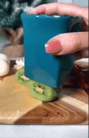 GIF of person cutting kiwi with a cup slicer