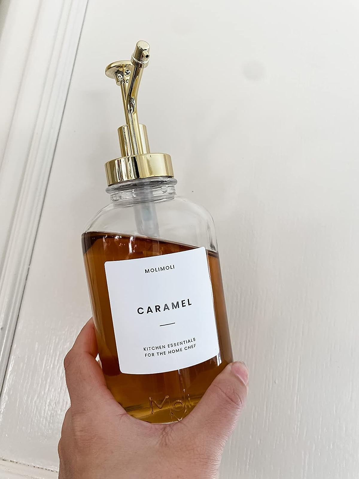 Reviewer holding up   the syrup vessel  with the caramel statement   connected  it