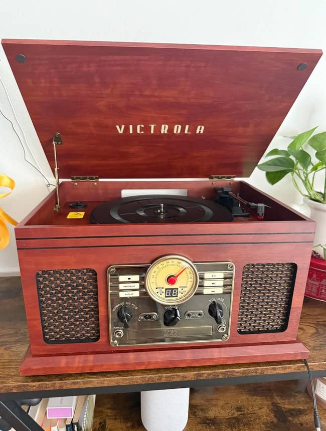 Victrola grounds subordinate with vintage design, featuring a built-in vigor and speakers. Lid is open, revealing the turntable
