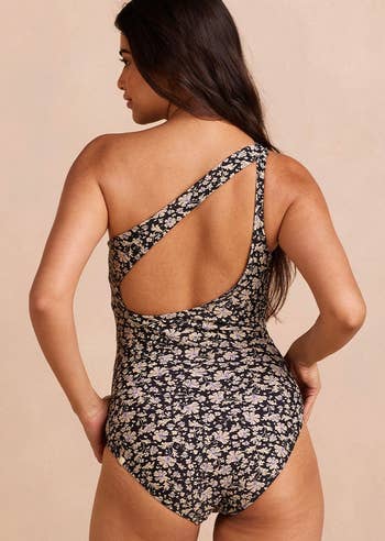 Woman in a one-piece floral swimsuit, viewed from behind, looking over her shoulder