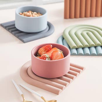 Stacked food containers with a bowl of fruit on a table, surrounded by kitchen accessories