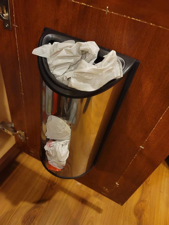 reviewer image of the plastic bag dispenser mounted on a kitchen cabinet door