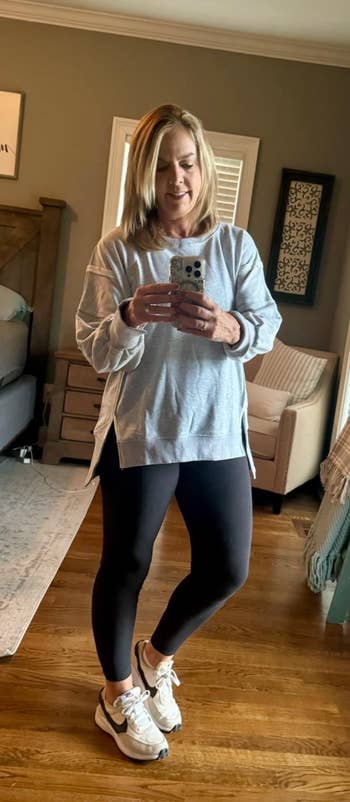 Person successful  a cozy country   taking a reflector  selfie, wearing a comfy  long-sleeve top, leggings, and sneakers