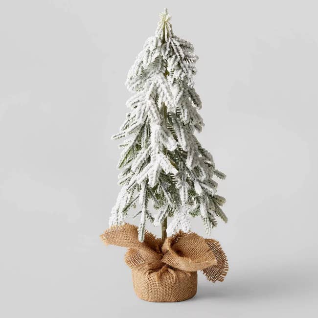 a small flocked tree with a burlap stand