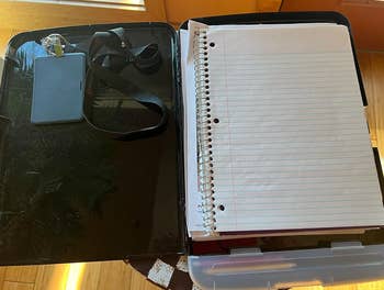 the clipboard open revealing internal storage with a notebook and work badge inside 