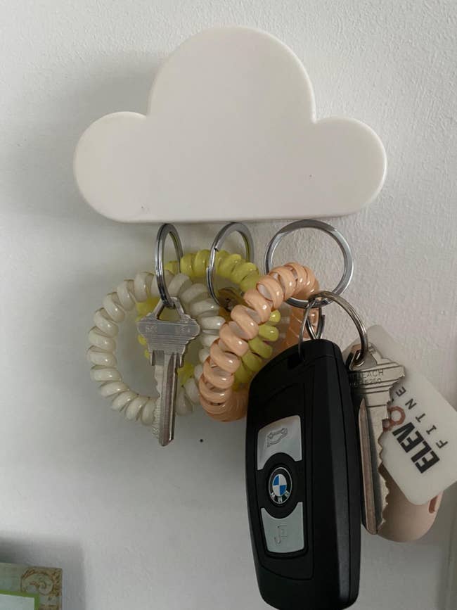 white cloud magnet holding up three sets of keys on a wall