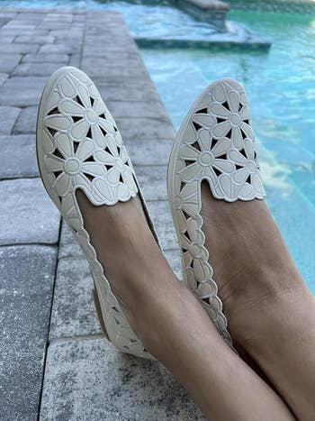 reviewer wearing beige floral cut-out flats beside a pool