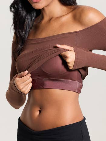 Person wearing a brownish  off-shoulder ribbed harvest  top, showcasing a seamless bra underneath
