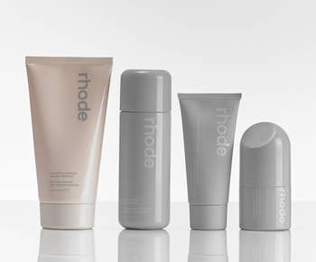 A collection of four Rhode skincare products on a reflective surface