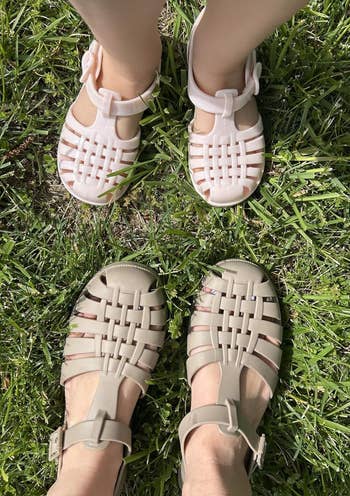 Two pairs of feet wearing stylish woven sandals connected grass, showcasing chic summertime footwear choices
