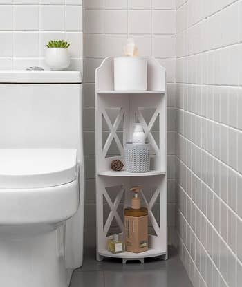 white corner shelf with toiletries and decorative items between toilet and wall