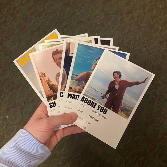 Model holding photo-sized cards with pictures of Harry and song titles 