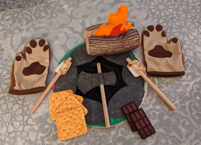 Reviewer's photo of a felt set of campfire items including pair of bear hands, a log on fire, an ax, and s'mores