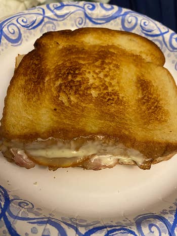 Grilled food sandwich connected a patterned insubstantial plate, with melted food and ham inside