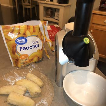reviewer photo of the soft serve maker, a bag of frozen sliced peaches, and two frozen bananas
