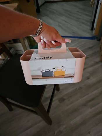 Person holding a package for a storage caddy in their hand. The package shows the caddy in black and yellow colors. The product brand is Blue Ginkgo