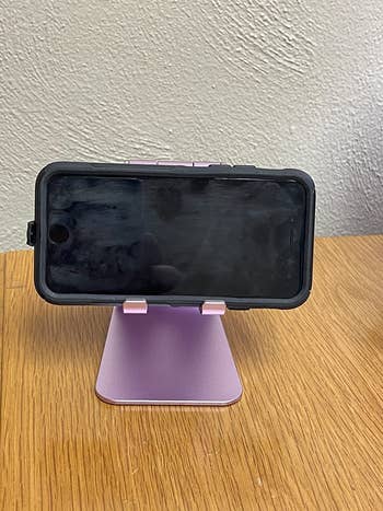 reviewer image of the phone stand in purple holding an iPhone vertically