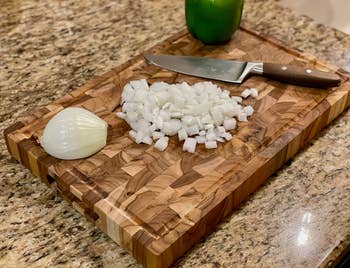 reviewer photo of the cutting board holding chopped onions and a knife