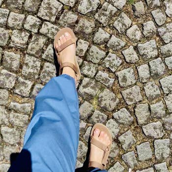Person successful sandals and bluish pants walking connected cobblestone