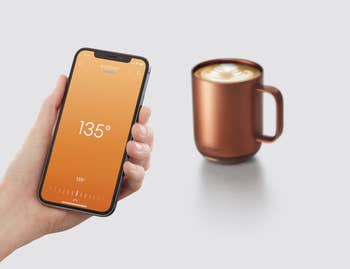 model holding a smartphone connected to the ember app in front of the mug