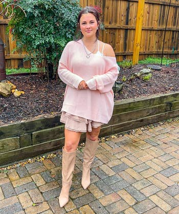 Person successful an oversized sweater, mini skirt, and knee-high boots stands connected a patio with plot decor down them