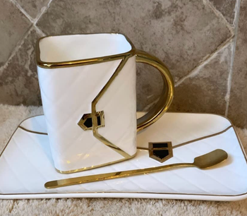 white version showing the mug tilted up with the handle of the purse as the handle of the cup 