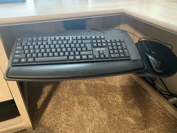 reviewer photo of the keyboard tray attached to the underside of their desk