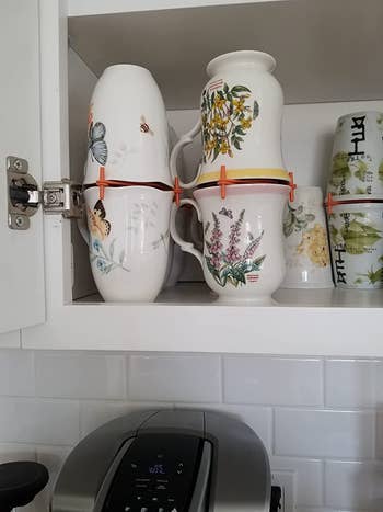 A cabinet filled with mugs stacked on top of each other using a mug organizer 