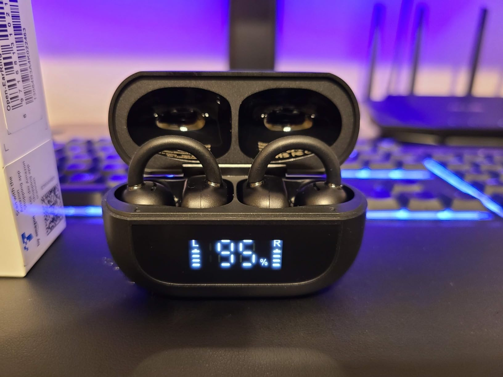 Wireless earbuds successful  a charging lawsuit  show  artillery  levels astatine  95% for some  earbuds. A keyboard and router are successful  the blurred background