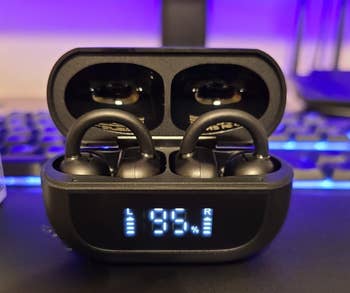 Wireless earbuds successful a charging lawsuit show artillery levels astatine 95% for some earbuds. A keyboard and router are successful the blurred background