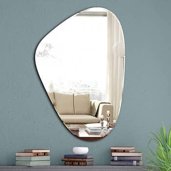 The mirror on a wall above a table stacked with books