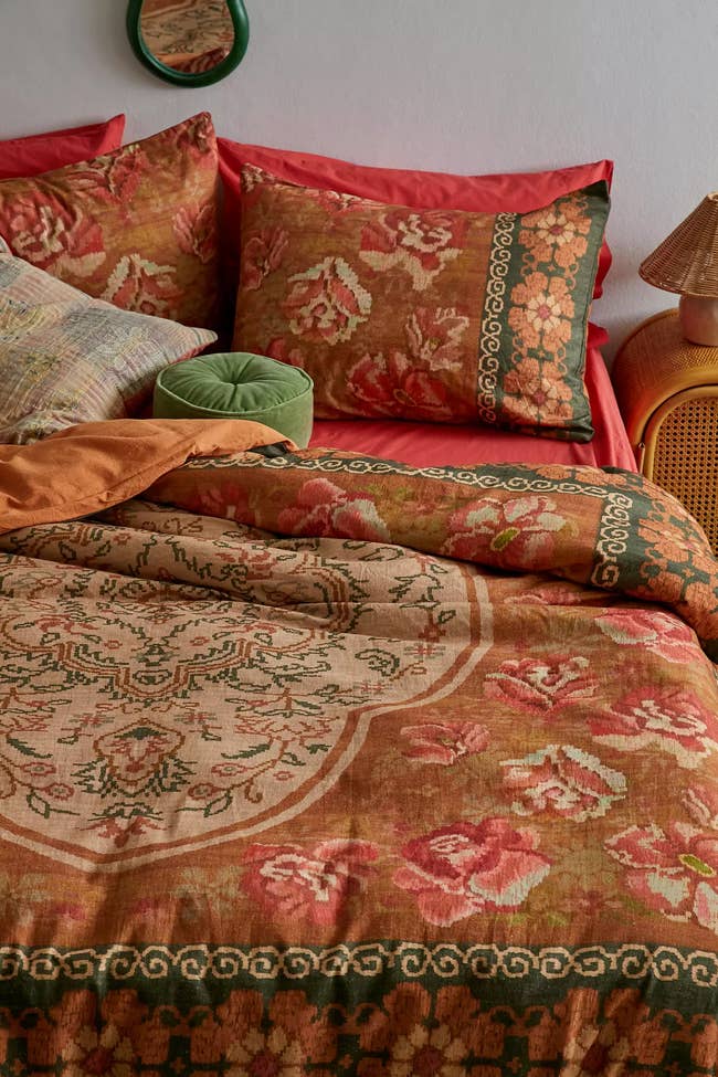 Floral-patterned bedding with decorative pillows and a woven bedside lamp, creating a cozy, inviting chamber setup