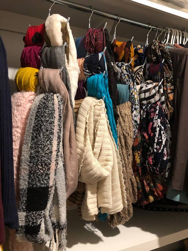 Assorted scarves hanging on a rack in a closet
