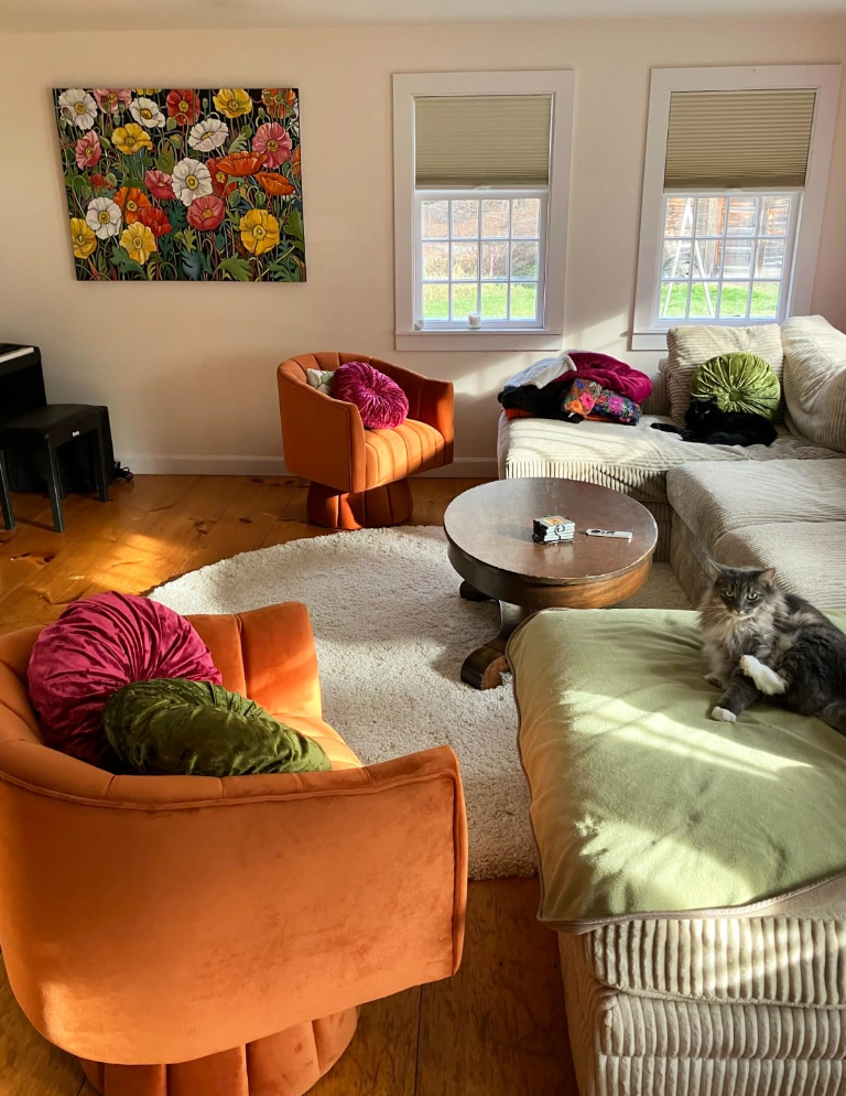 A cozy surviving  country   with a feline  connected  the couch, adjacent armchairs, a java  table, and a floral coating  above