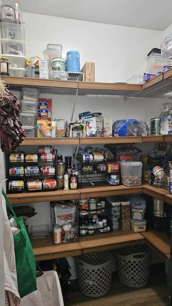 Organized pantry with shelves afloat of canned goods, jars, spices, and containers. Various groceries and room supplies are neatly arranged
