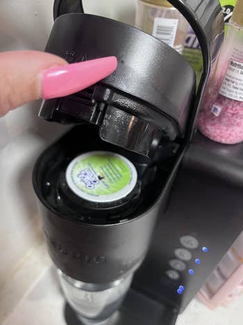 Hand placing a K-Cup pod successful a java machine, preparing a brew. Nearby ingredients suggest a flavored java oregon dessert-themed drink