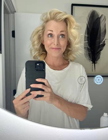 Person takes a reflector  selfie successful  a bath  wearing a casual t-shirt with wavy hairsbreadth  styled