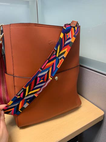 A closeup of the bag in brown with a colorful strap